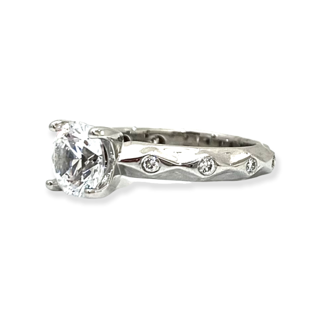 White gold diamond solitaire engagement ring three-quarter view with bezel-set diamonds along the wavy band