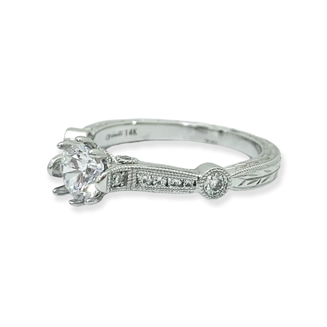 Angled view of a white gold solitaire ring with a round diamond and engraved band marked 14K