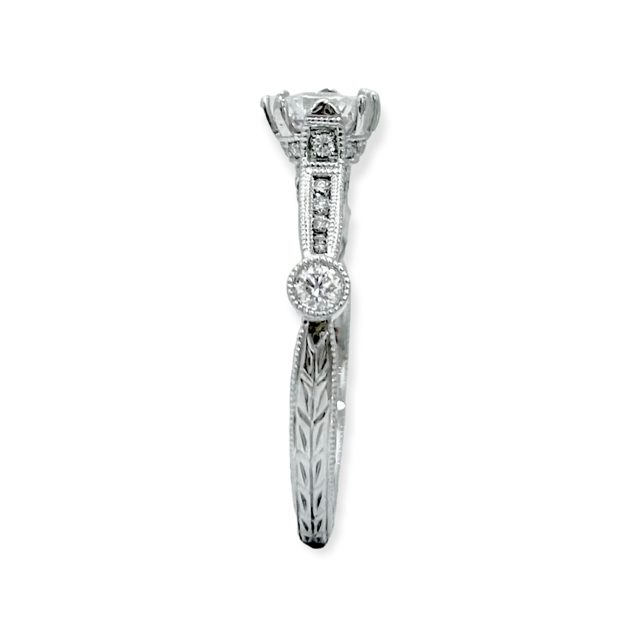 Side view of a white gold solitaire ring with a bezel diamond accent and engraved band
