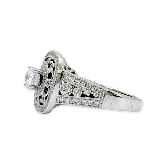 Angled side view of a white gold vintage-style diamond halo ring marked 14K