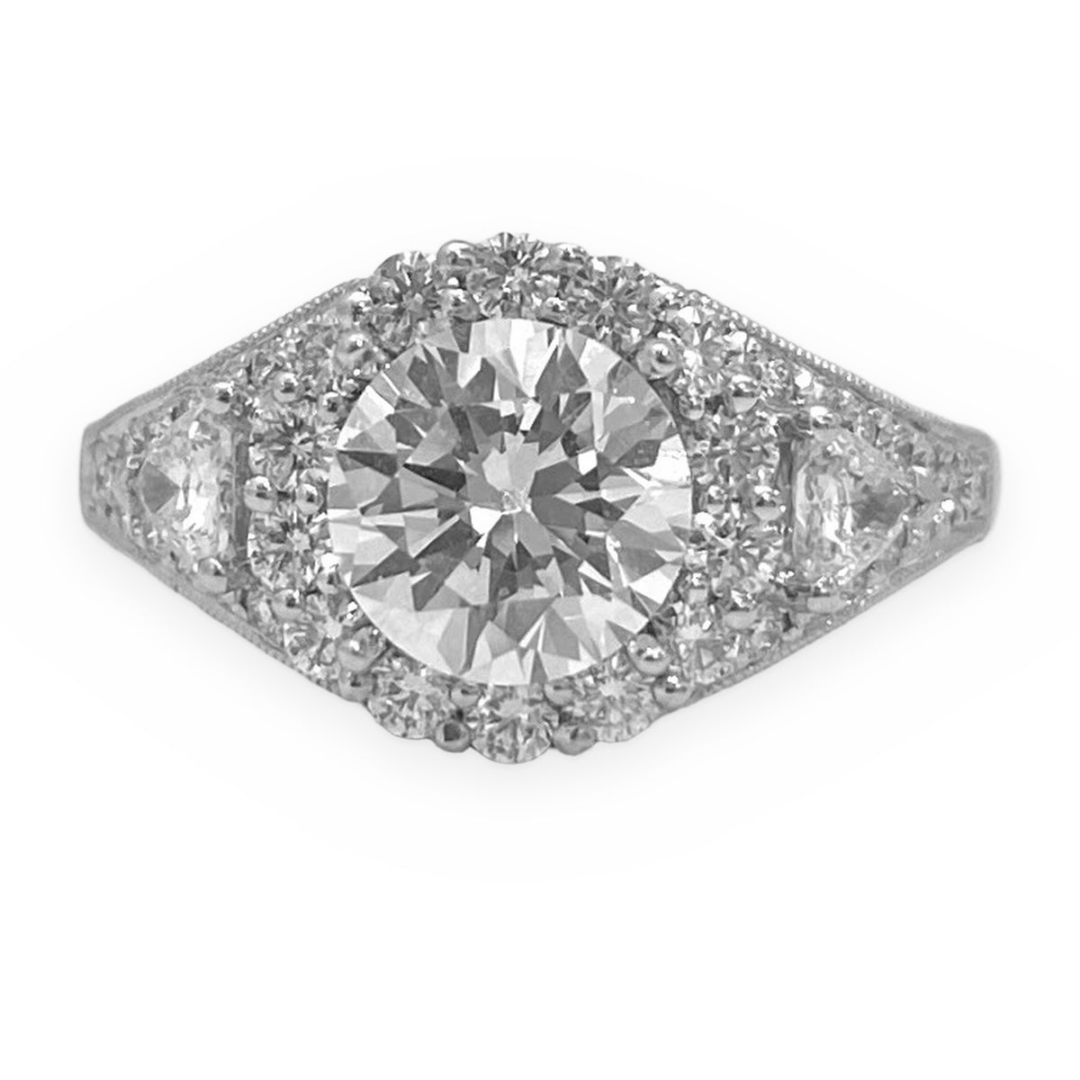 White gold round diamond halo engagement ring with three-stone design, close-up on textured surface
