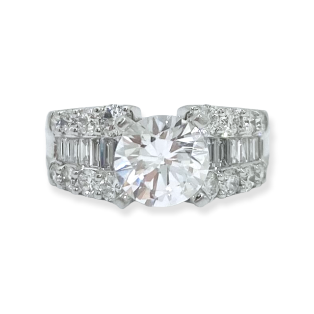 White gold round diamond engagement ring with baguette and round accents on a wide band