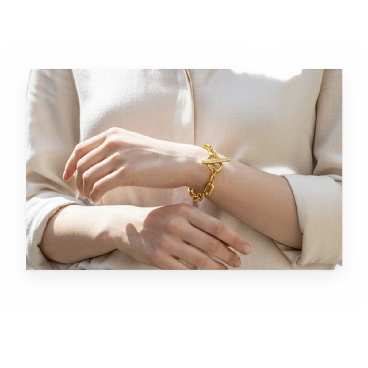 Yellow gold paperclip link toggle bracelet worn on a model's wrist