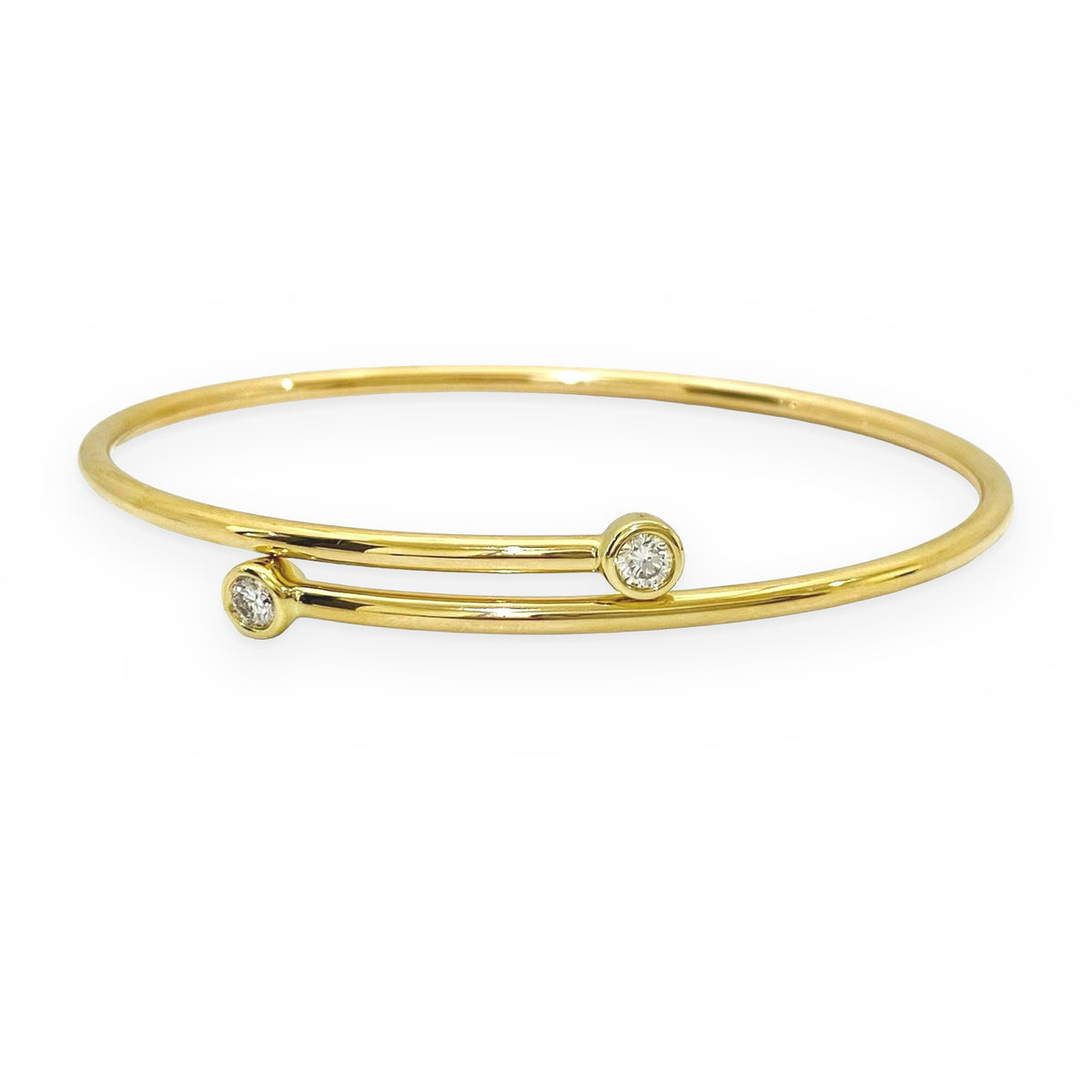 Yellow gold bypass bangle with two round bezel-set diamond terminals