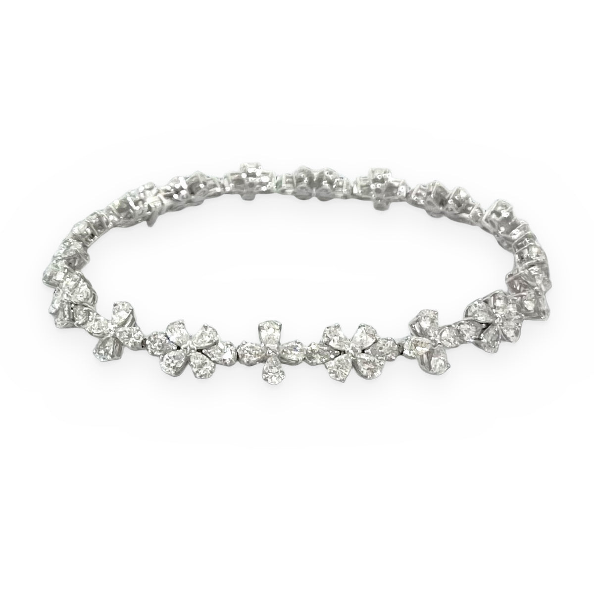 White gold diamond floral cluster bracelet on a soft gray surface