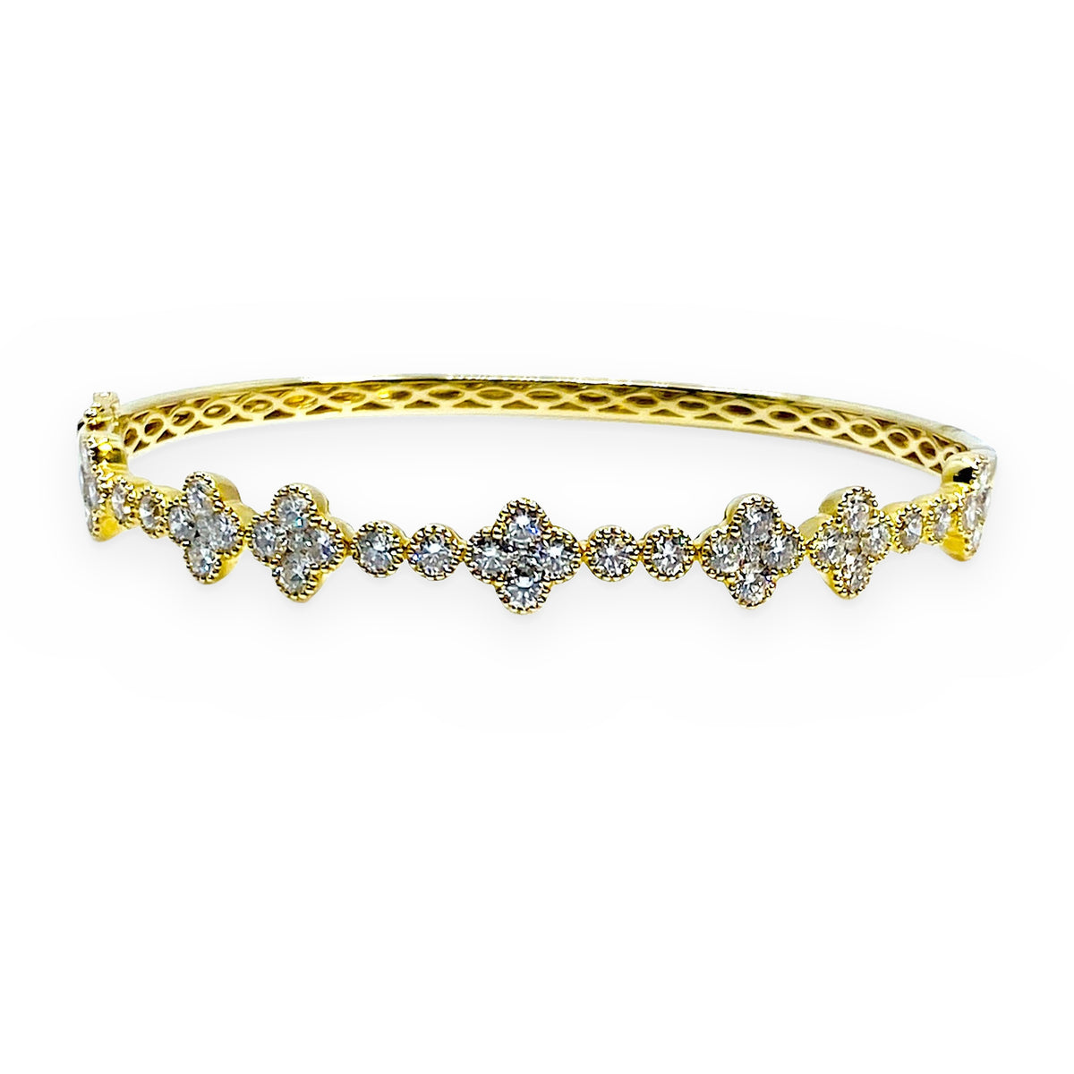 Yellow gold quatrefoil diamond cluster bangle shown at an angle with openwork gallery