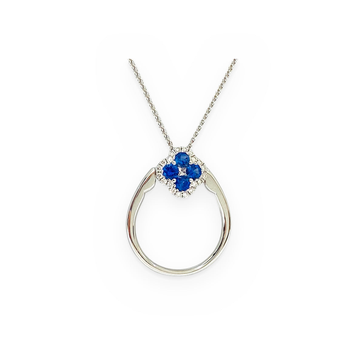 White gold sapphire clover pendant with diamond halo hanging on a chain