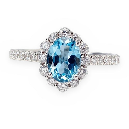 White gold ring with an oval blue topaz in a floral diamond halo