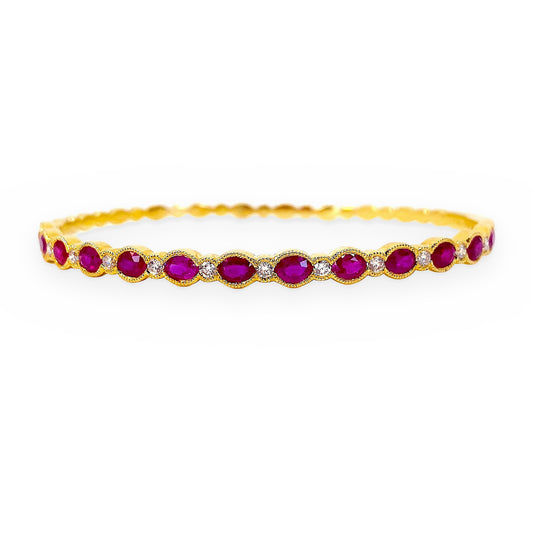 Yellow gold bangle bracelet with oval rubies and diamond accents in milgrain settings