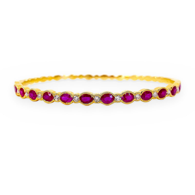 Yellow gold bangle bracelet with oval rubies and diamond accents in milgrain settings