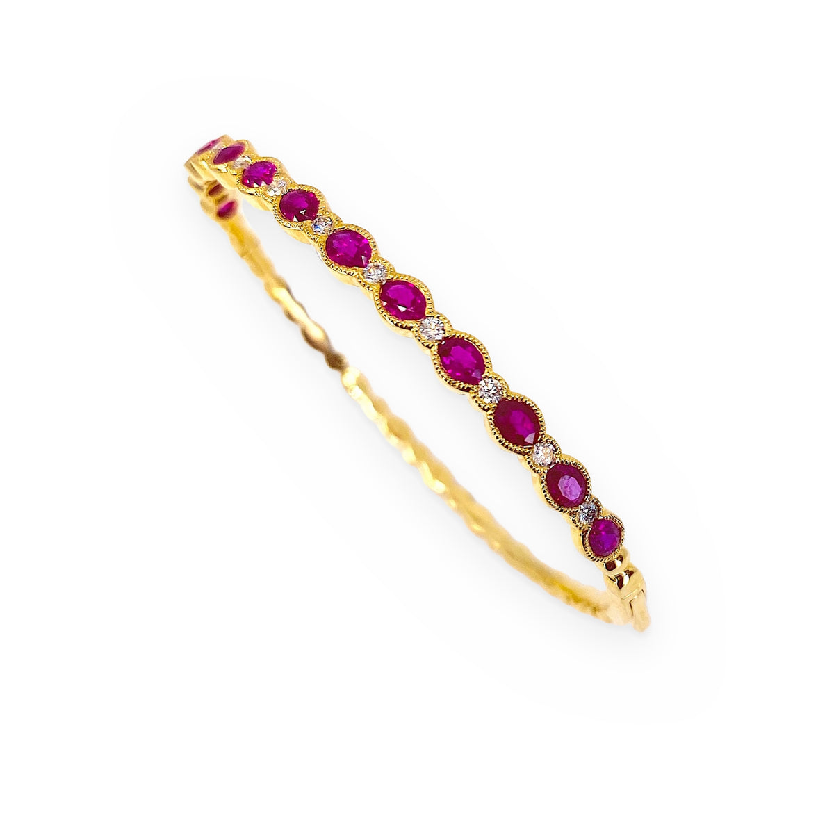 Yellow gold ruby and diamond bangle bracelet shown at a three-quarter angle