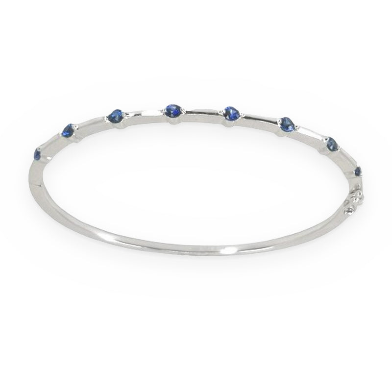 White gold thin sapphire-station bangle bracelet shown at a three-quarter angle