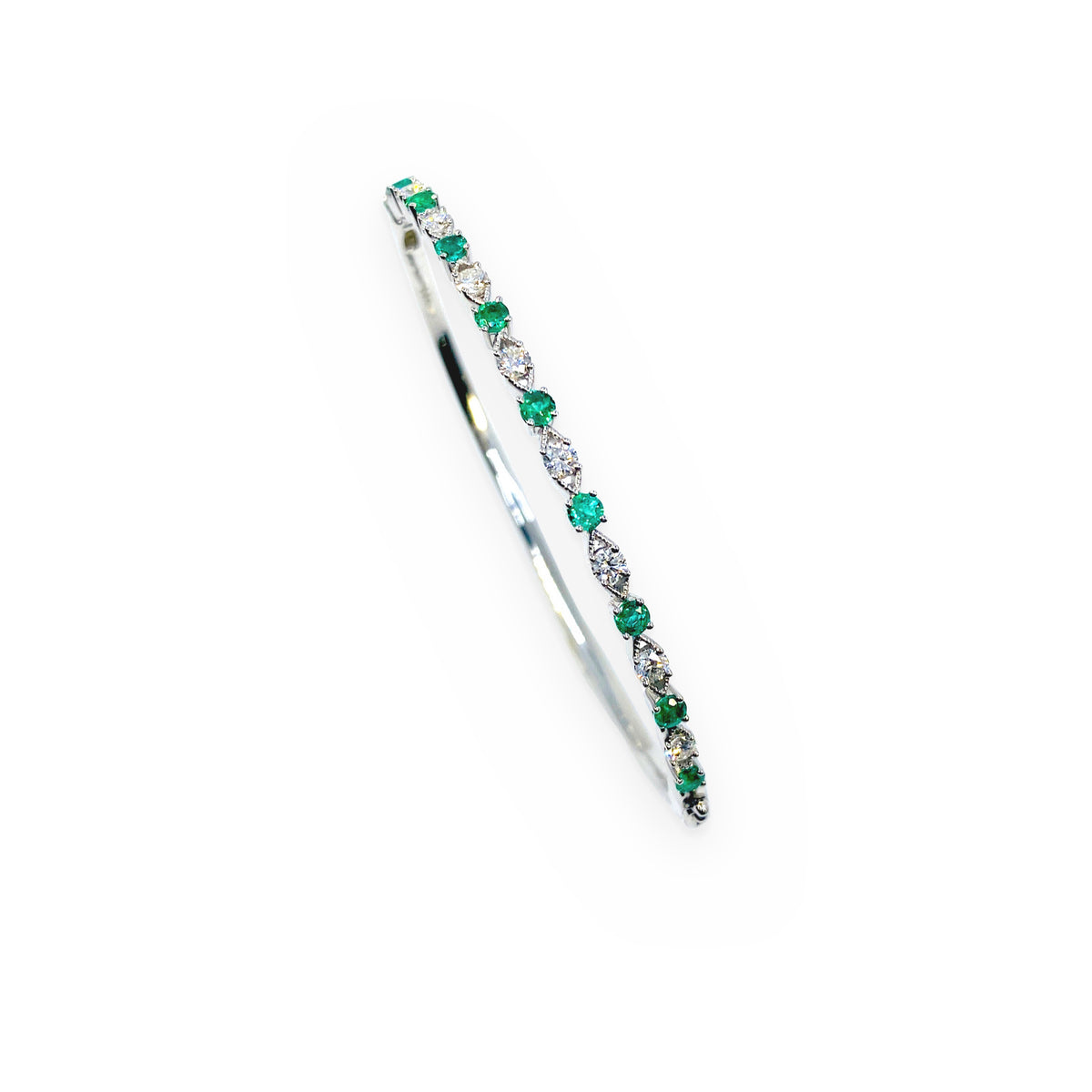 White gold emerald and diamond bangle bracelet shown at a three-quarter angle