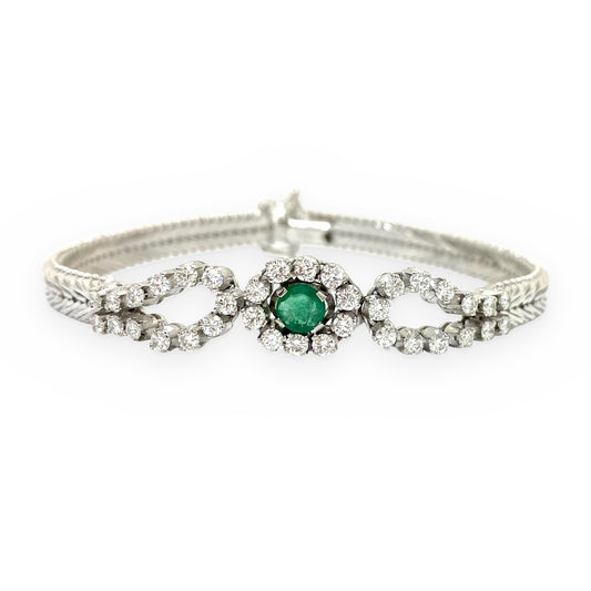 White gold vintage bracelet with a round emerald center flanked by looping diamond swirls