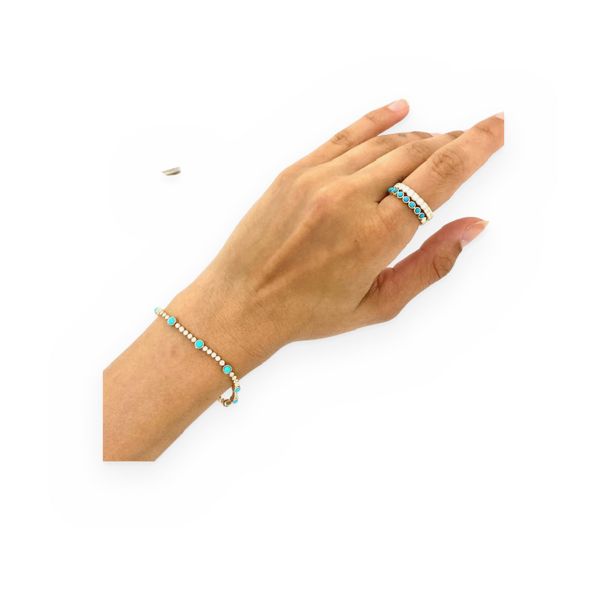 Yellow gold turquoise and diamond bracelet and matching stacked rings worn on a model's hand