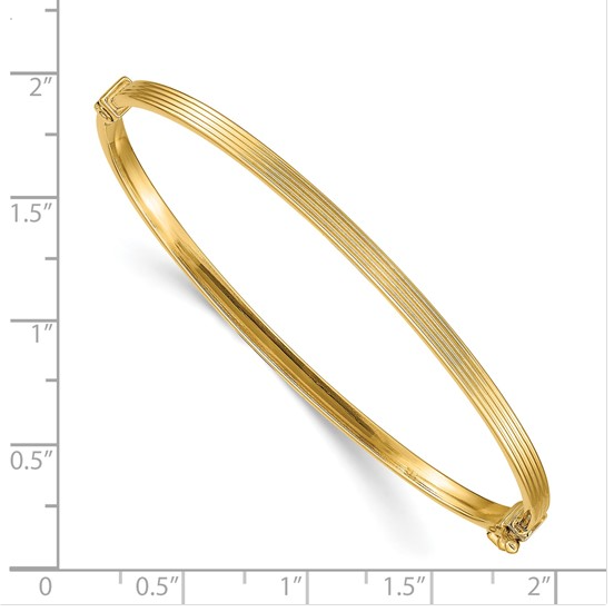 Yellow gold ridged hinged bangle shown against a ruler for scale