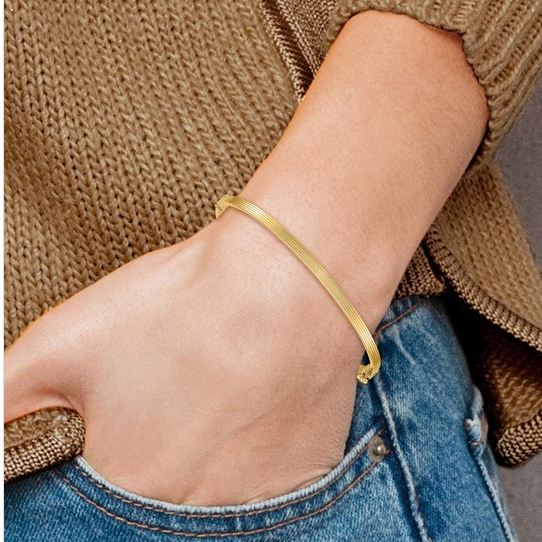 Yellow gold ridged bangle worn on a model's wrist