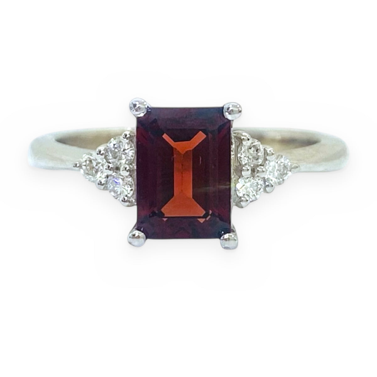 White gold ring with emerald-cut red garnet flanked by diamond clusters