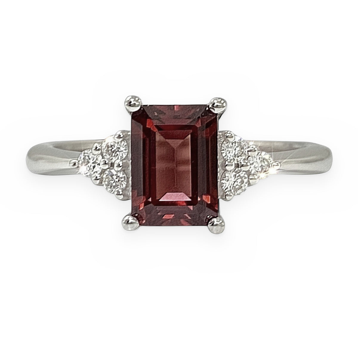 White gold ring with emerald-cut red garnet and side diamond clusters, close view