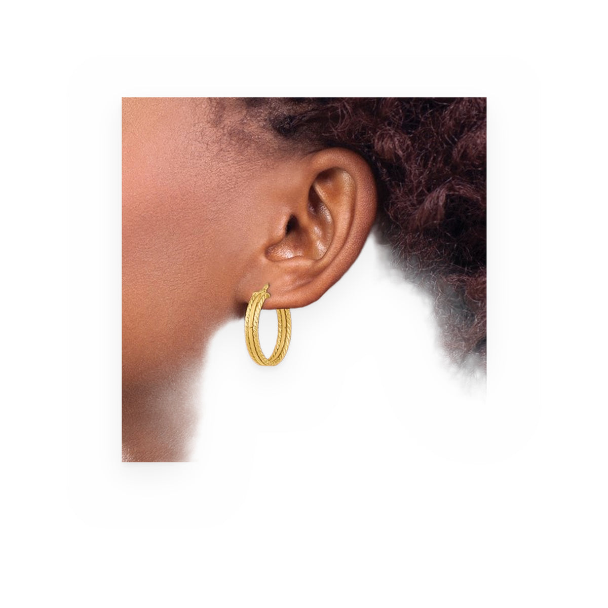 Yellow gold twisted-rope hoop earring worn on model's ear